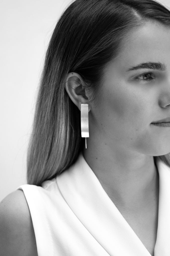 Model wearing handmade statement rectangular silver earrings. 