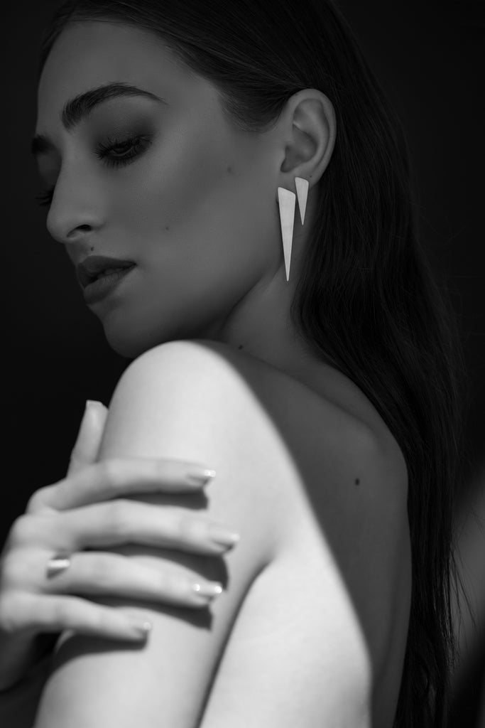 Minimalist small and large triangle silver earrings on a model. Artistic black and white picture.