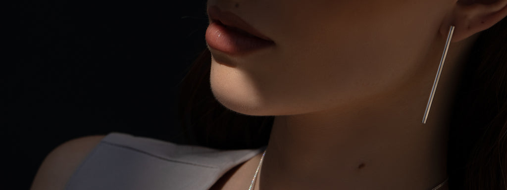 Model wearing minimalist long tube silver earrings.