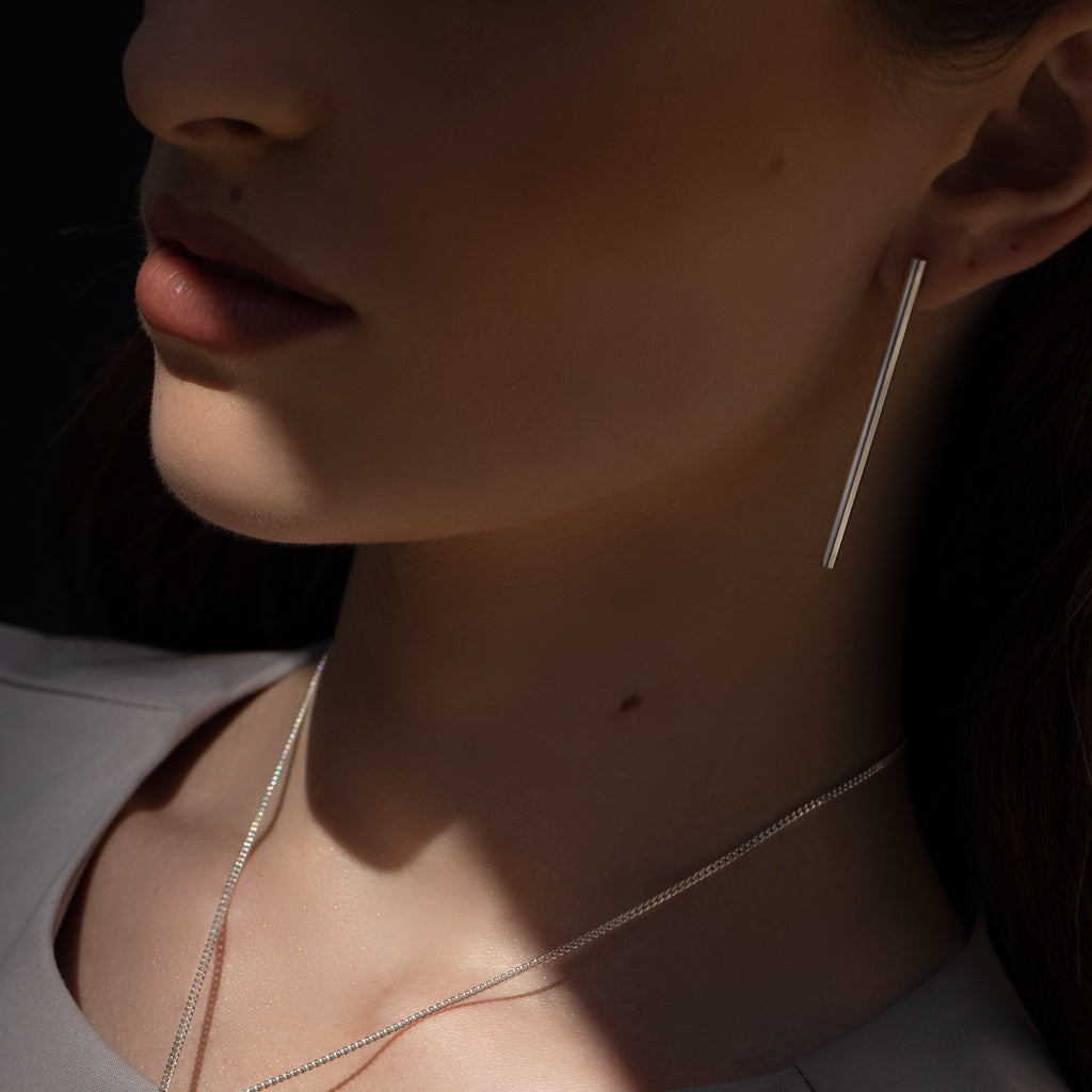 Model wearing minimalist long tube silver earrings